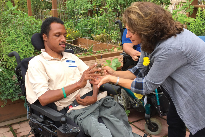 A community member participates in horticultural therapy with Anne Meore, Registered Horticultural Therapist.