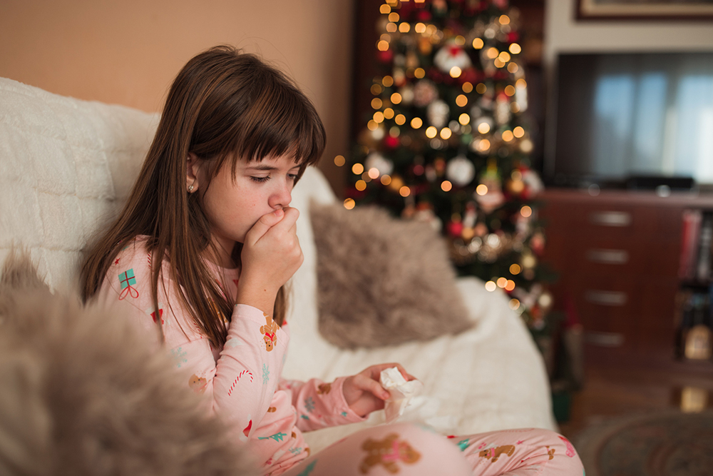Girl coughing in front of Christmas tree