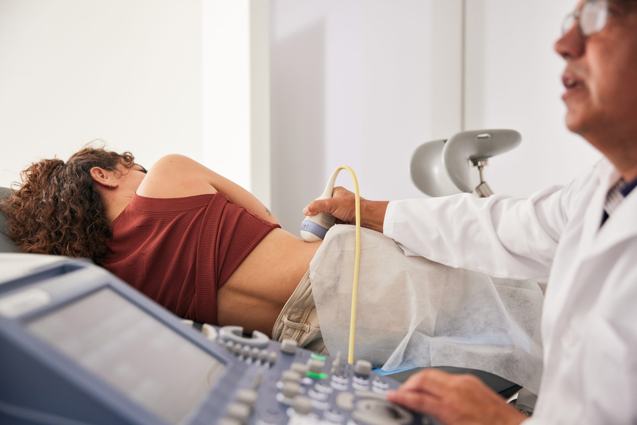 Doctor examining the woman's right kidney using an ultrasound scanner