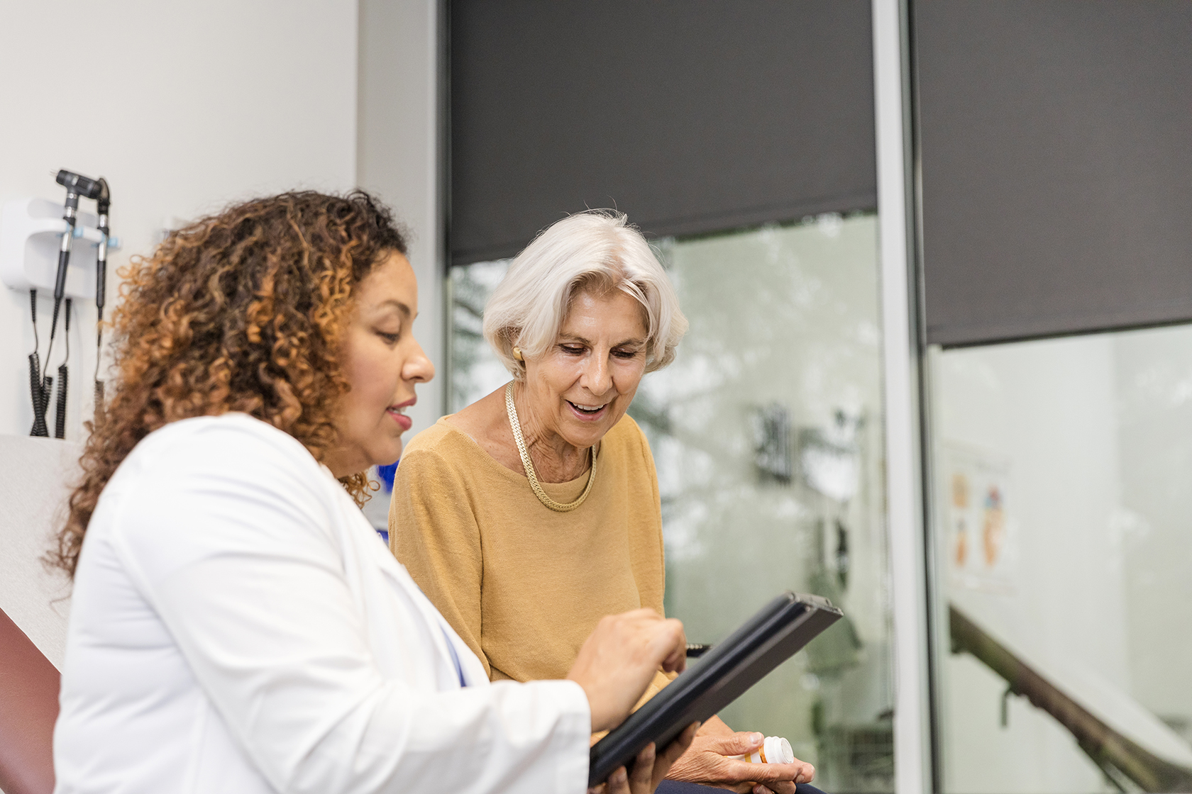 Direct Access Colon Cancer Screening Program The senior adult woman sits with her doctor in the office to ask a question about her electronic medical record.