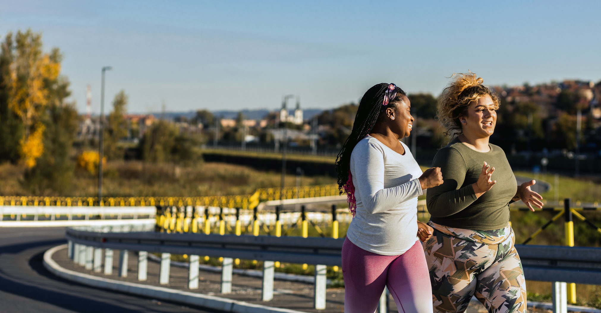 Two young women jogging together outside on a road