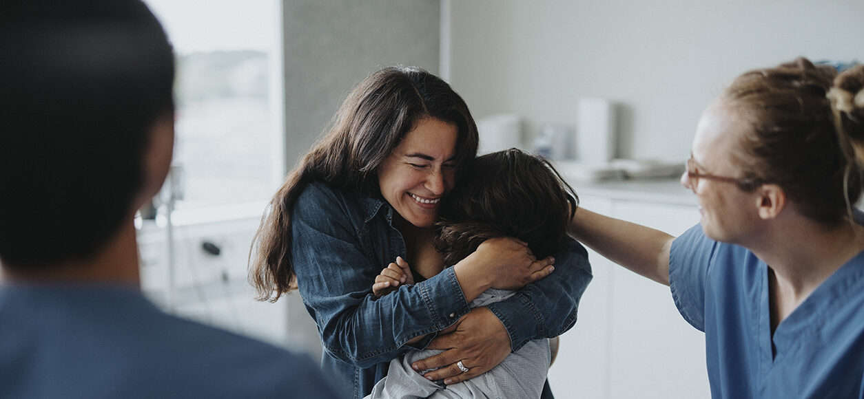 Happy woman embracing son after receiving good news at healthcare center