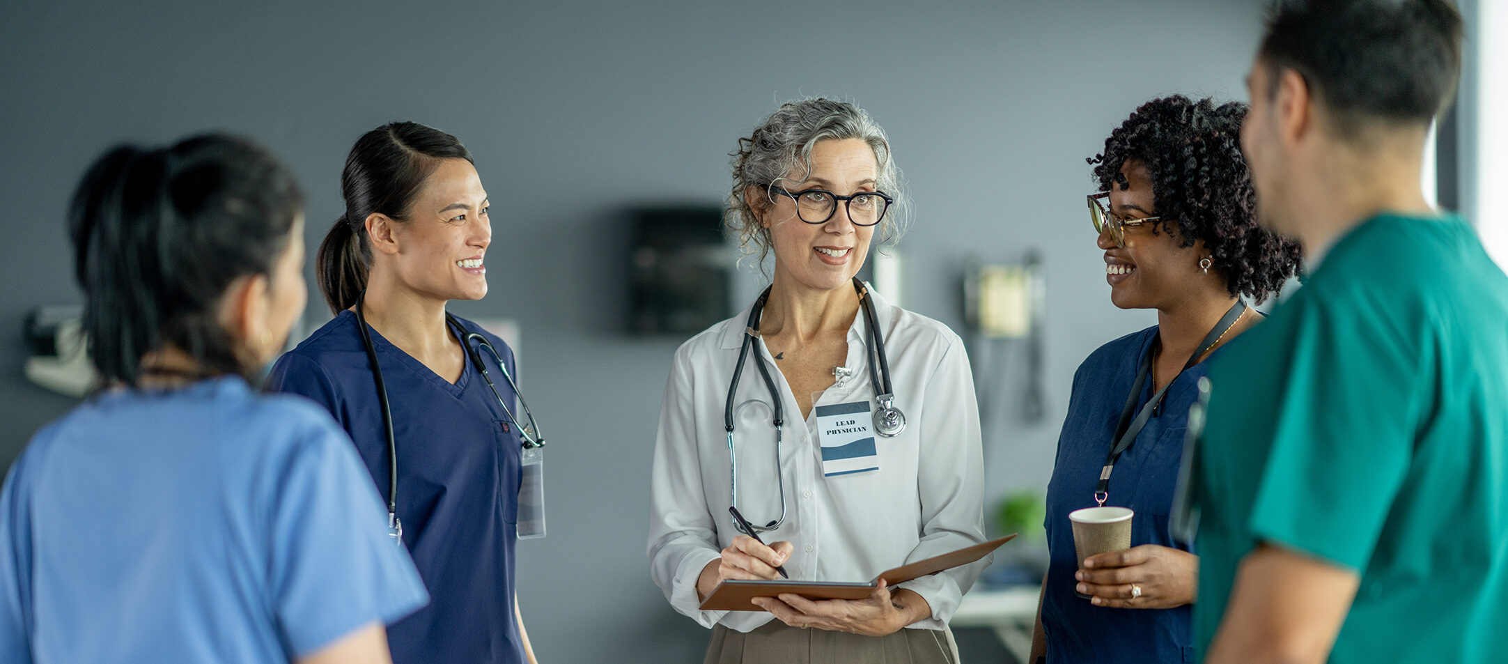 A Day in the Life of a Hospitalist: The Backbone of Inpatient Care A team of medical professionals wearing uniforms discusses patient care in a hospital environment, exhibiting teamwork, communication, and collaboration critical to providing effective healthcare services.
