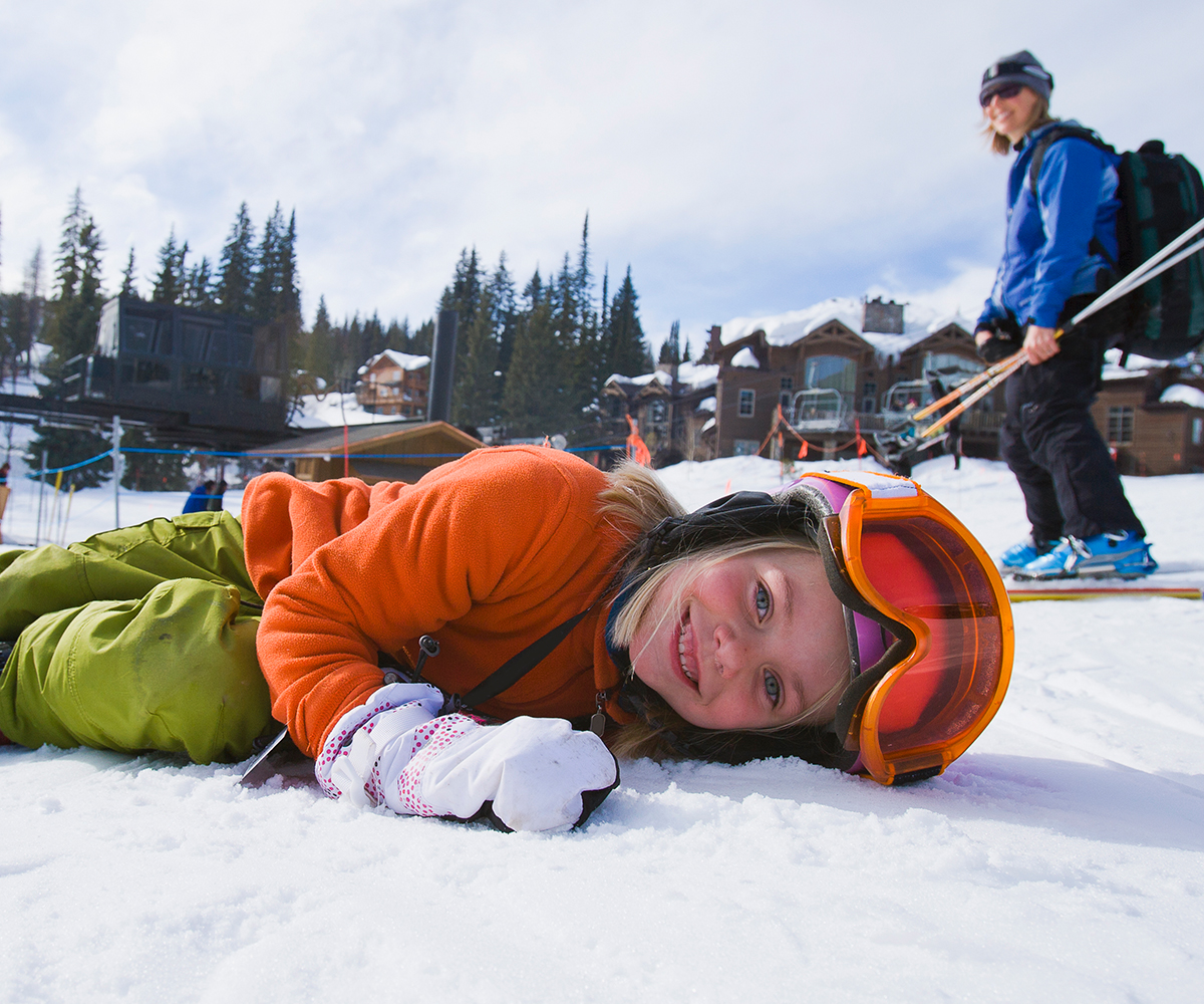 Child in ski gear lying on snow