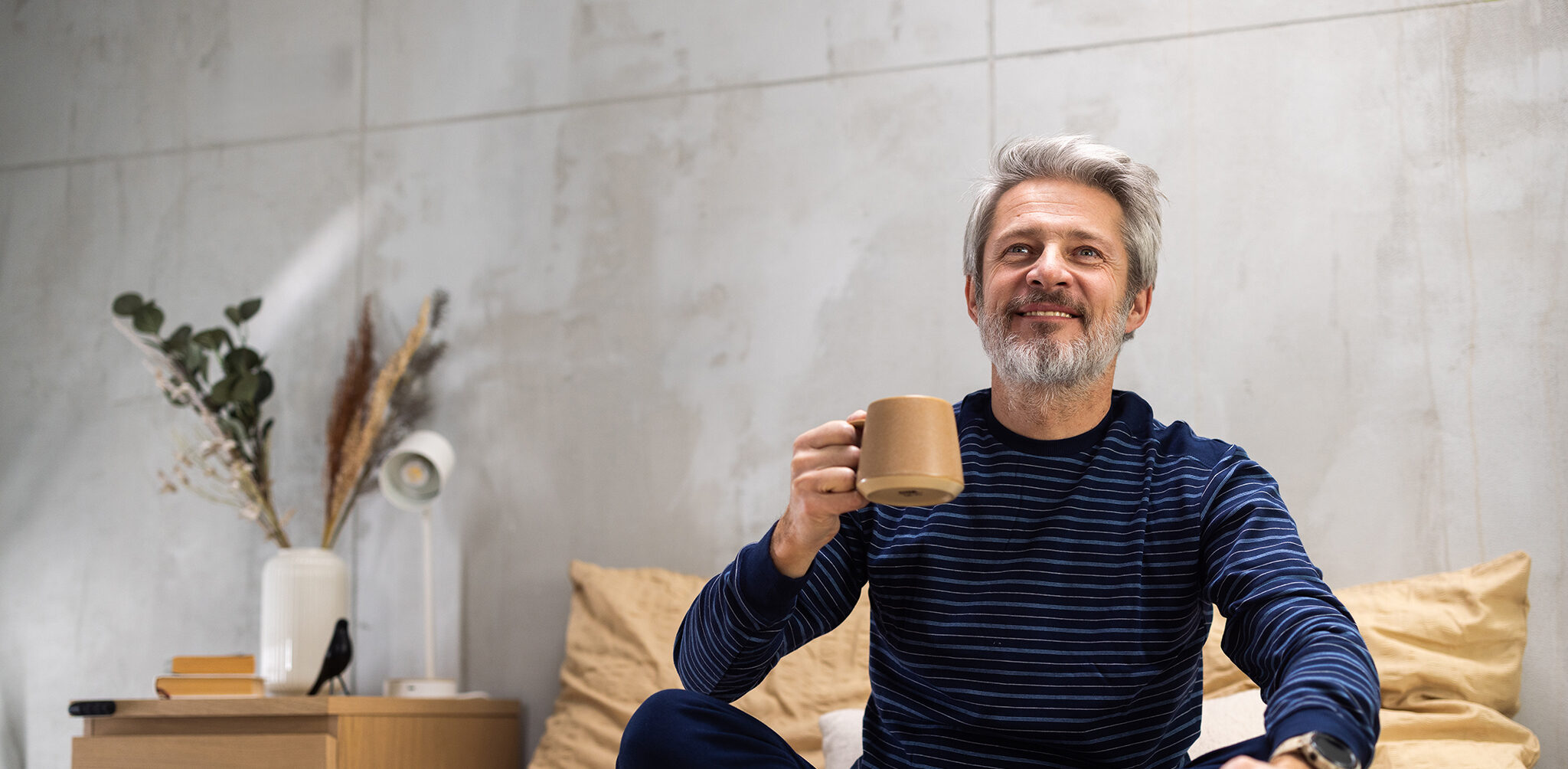 The Sleep-Brain Health Connection: What Your Sleep Says About Your Neurological Health Mature man relaxing on bed, drinking hot coffee from a mug, and looking away