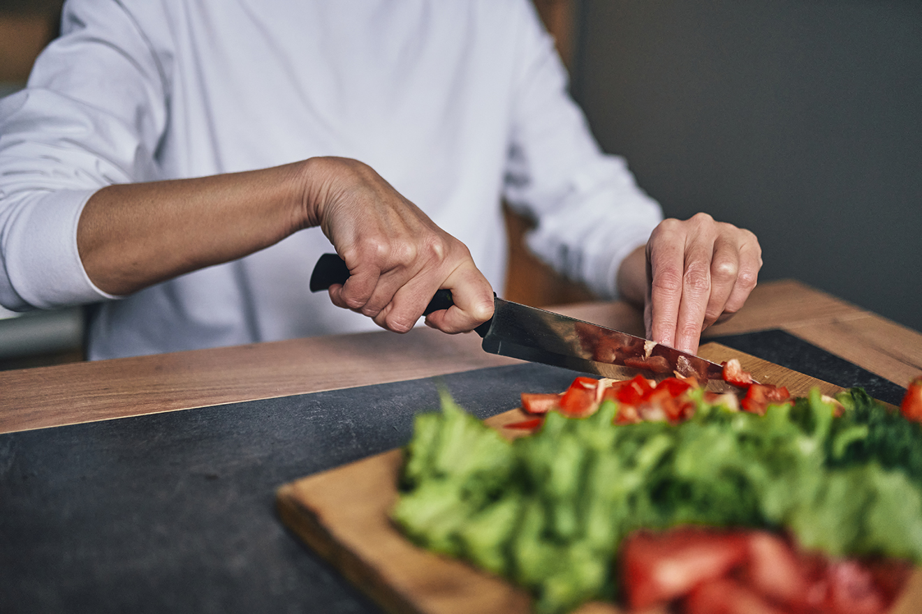 Person cutting vegetables on a wooden chopping board