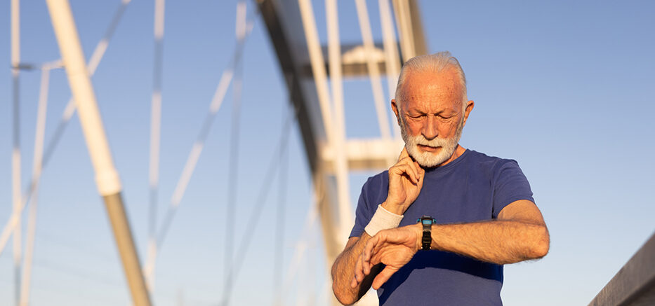 Older male checking his pulse on his neck over a bridge