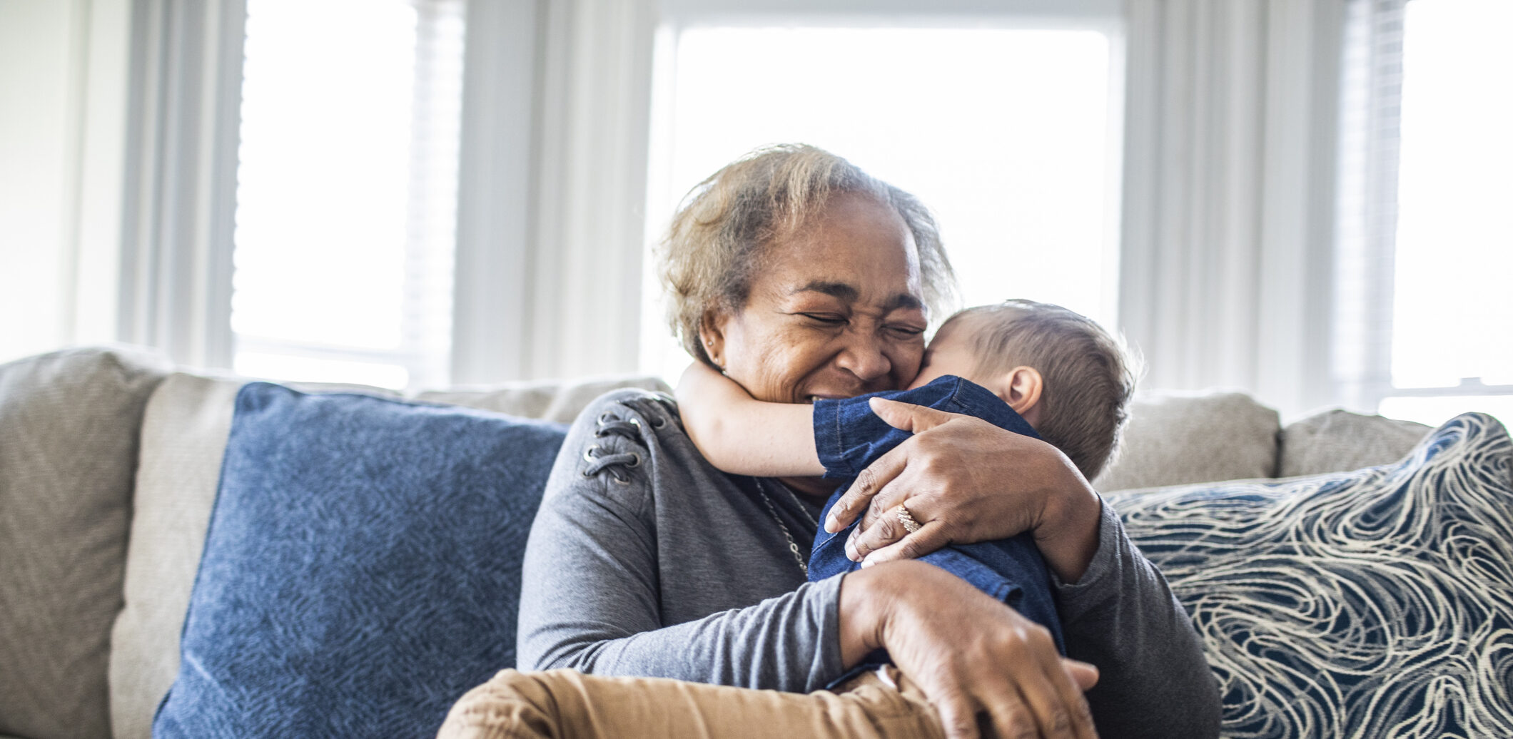 Grandmother embracing toddler grandson and laughing