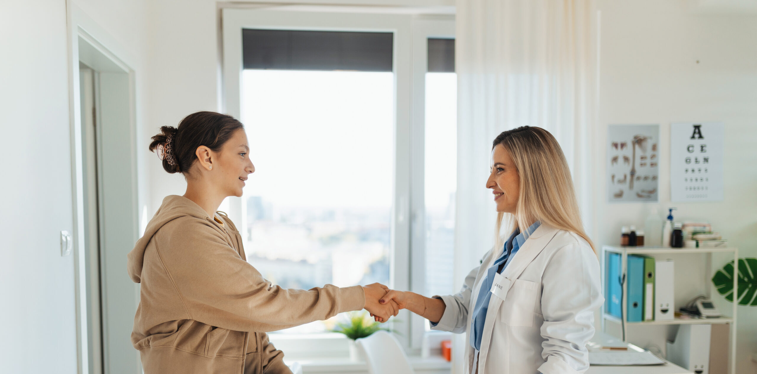 Teenage patient arriving at appointment with doctor, shaking hands with female pediatrician, physician. Teen girl have consultation, first visit with gynecologist. Concept of preventive health care for adolescents.
