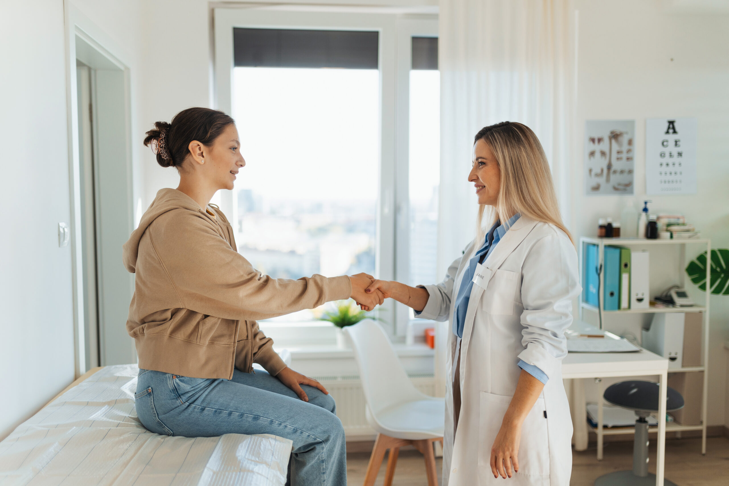 Teenage patient arriving at appointment with doctor, shaking hands with female pediatrician, physician. Teen girl have consultation, first visit with gynecologist. Concept of preventive health care for adolescents.