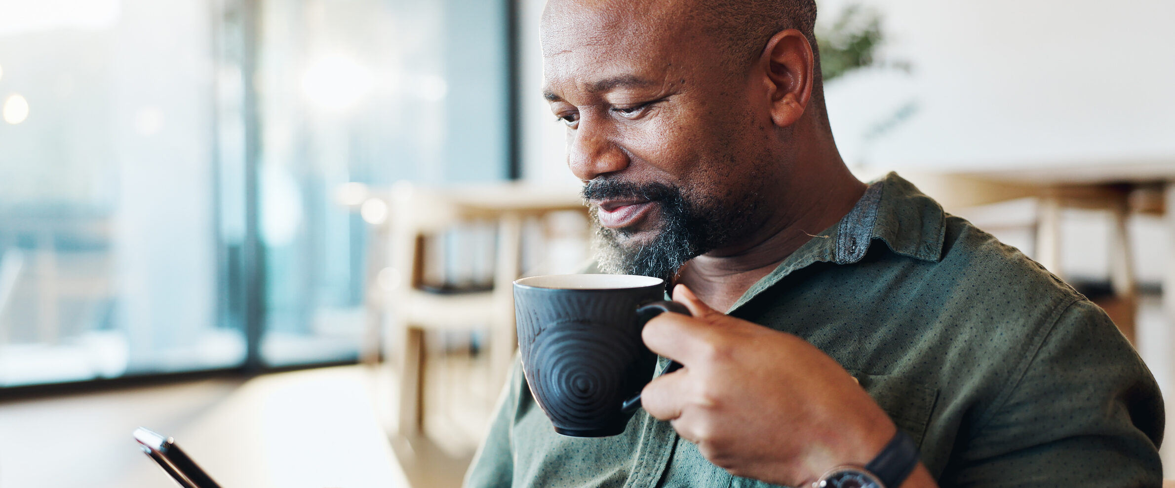 Mature black man, phone and coffee in home with thinking, smile and reading email notification in morning. Person, smartphone and happy with tea, news and scroll on social media with mobile app
