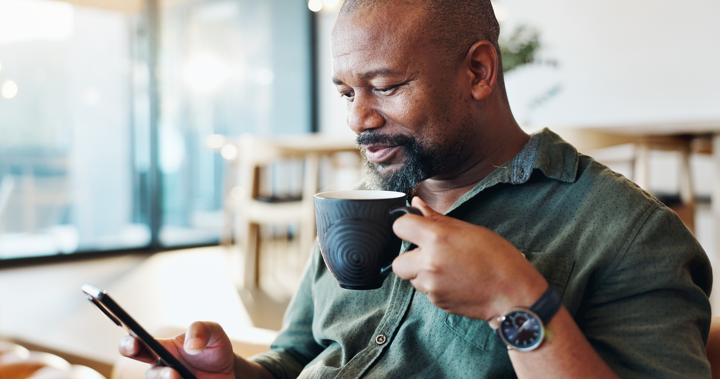 Could You Benefit from Lung Cancer Screening? Mature black man, phone and coffee in home with thinking, smile and reading email notification in morning. Person, smartphone and happy with tea, news and scroll on social media with mobile app