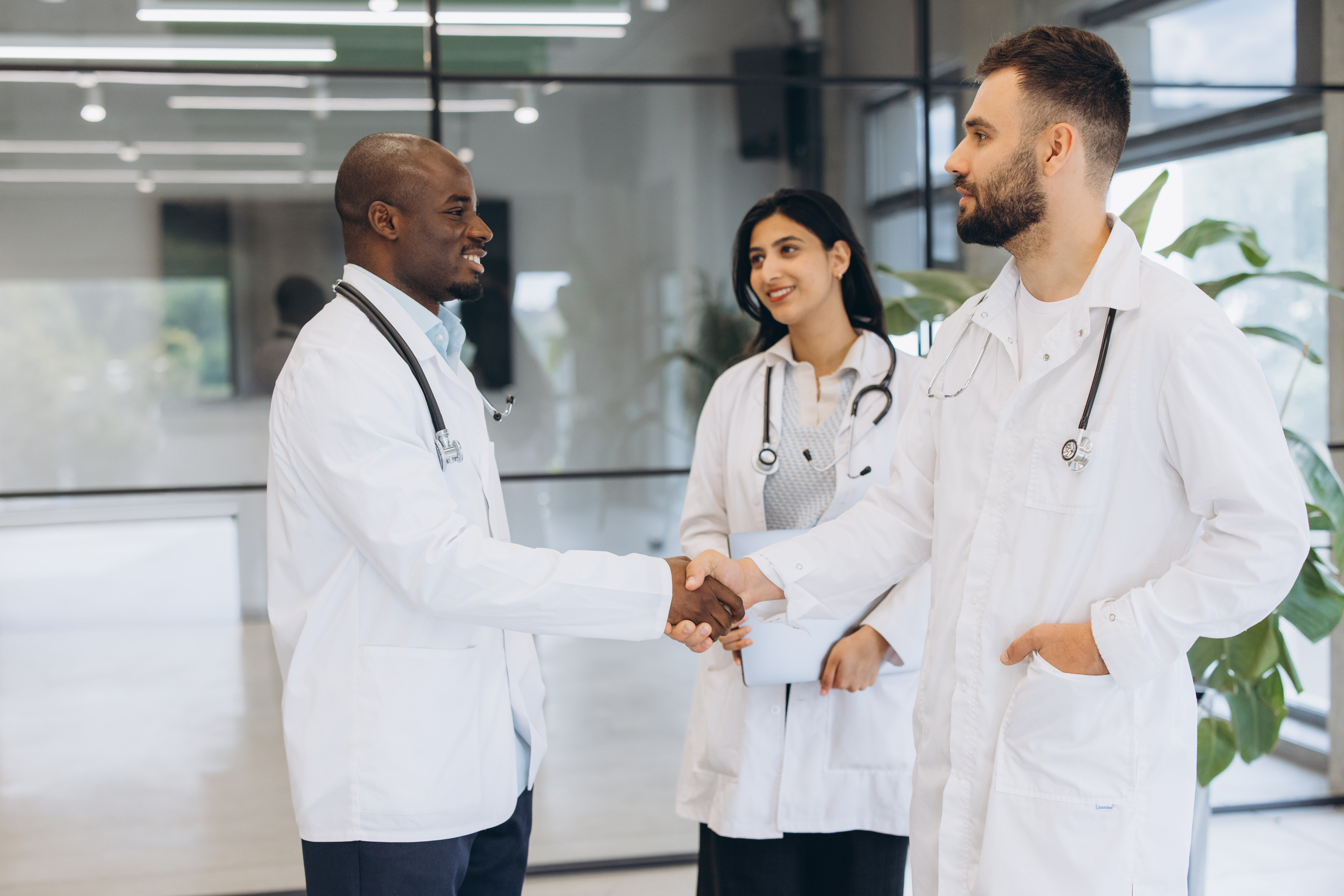 Doctors from diverse backgrounds shaking hands, showing agreement and partnership in a modern medical facility