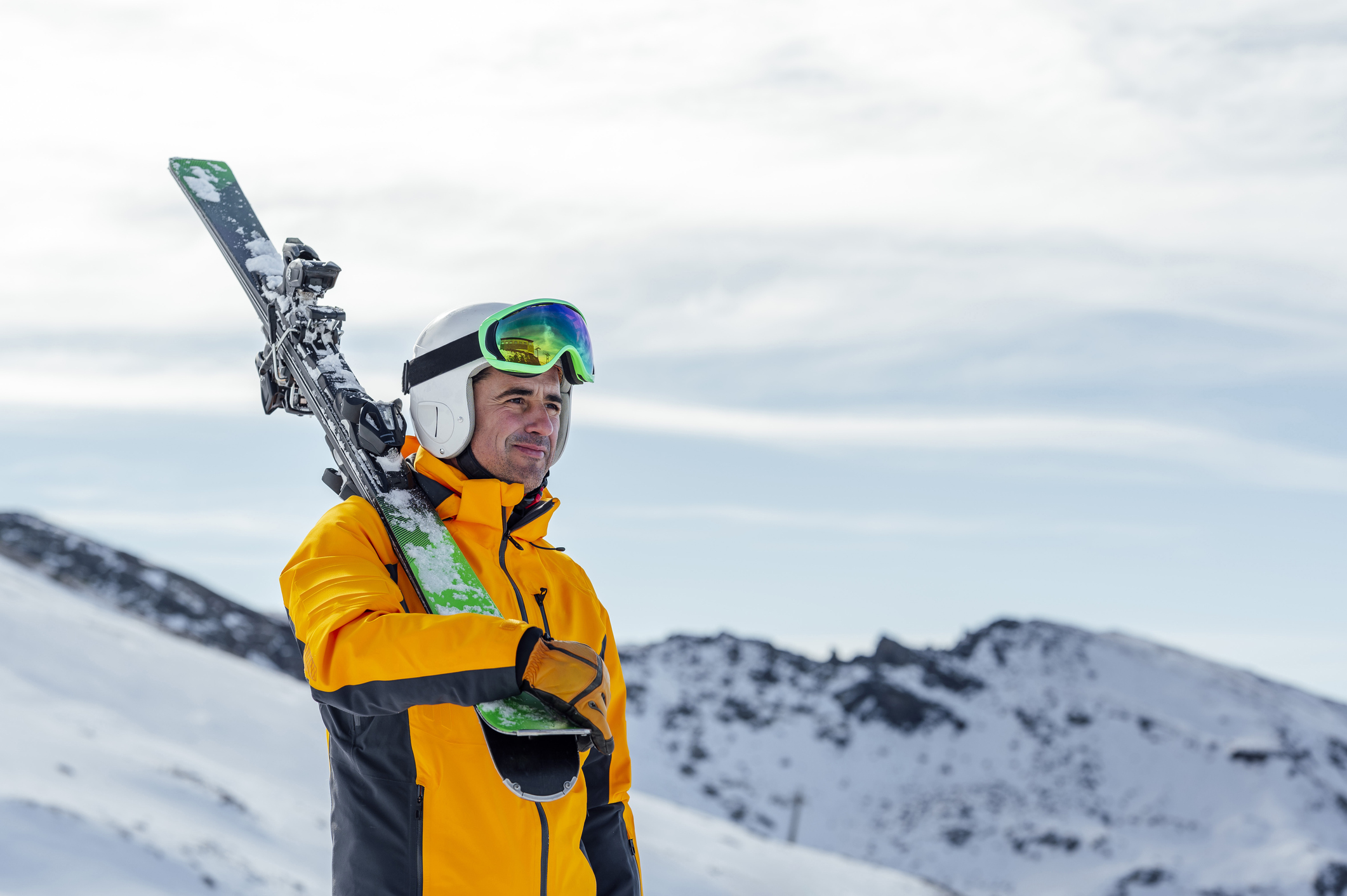 Man with ski looking away while walking on snow covered valley